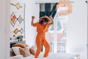 Silver Spring apartment for rent - A person in an orange outfit is dancing in a room with a window and a bed.
