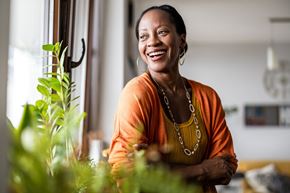 Silver Spring apartment for rent - A woman in an orange top is standing in front of a window with a plant beside her.