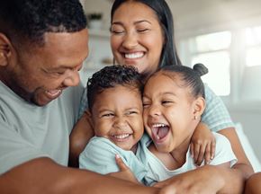 Arlington apartment for rent - A family of four is hugging and smiling together in a bright room.