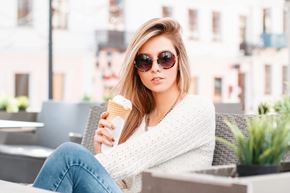 Arlington apartment for rent - A woman in a white sweater and blue jeans is sitting on a chair holding an ice cream cone.