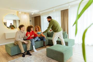 Silver Spring apartment for rent - A man serving food to two people sitting on a green couch in a living room.