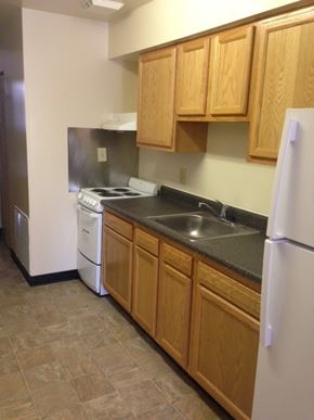 Baltimore apartment for rent - A kitchen with a white refrigerator, a black stove, and a dishwasher.