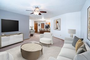 Fargo apartment for rent - A living room with a white couch, a wooden coffee table, and a flat screen TV. Fargo, ND Cedars 4 Apartments