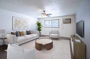 Fargo apartment for rent - A living room with a white couch, a brown coffee table, and a flat screen TV. Fargo, ND Cedars 4 Apartments