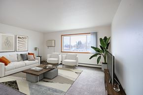 West Fargo apartment for rent - A living room with a white couch, two chairs, a coffee table, and a television. West Fargo, ND Saddlebrook Apartments