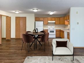 Bismarck apartment for rent - A kitchen with a table and chairs in the foreground. Bismarck, ND Sierra Ridge Apartments