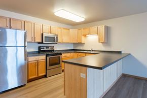 Moorhead apartment for rent - A kitchen with wooden cabinets and a black countertop. Moorhead, MN Sandy Creek Apartments