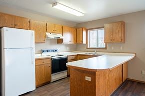 Fargo apartment for rent - A kitchen with wooden cabinets and a white refrigerator.