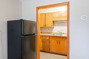 Fargo apartment for rent - A black refrigerator is in a kitchen with wooden cabinets. Fargo, ND Birchwood Apartments