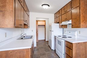 Fargo apartment for rent - A kitchen with wooden cabinets and a white stove top oven. Fargo, ND Carr Apartments