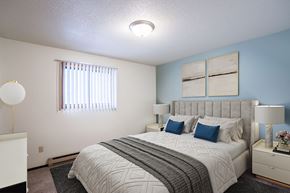 Fargo apartment for rent - A bedroom with a large bed and a window with blinds. Fargo, ND Countryside Apartments