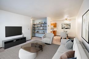Fargo apartment for rent - A living room with a grey sofa, a glass coffee table, and a television. Fargo, ND Countryside Apartments