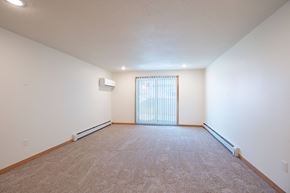 Grand Forks apartment for rent - A spacious room with a carpeted floor and a window with blinds. Cherry Creek Apartments