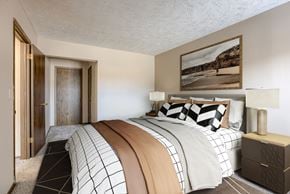Omaha townhouse for rent - A bedroom with a large bed and a painting on the wall. Omaha, NE Stony Brook Apartments