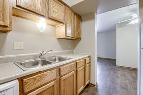 Omaha townhouse for rent - A kitchen with wooden cabinets and a white dishwasher. Omaha, NE Stony Brook Apartments