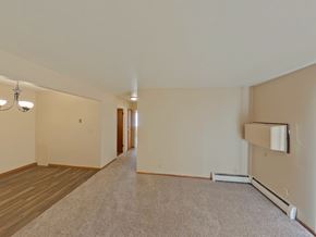 Crookston apartment for rent - A spacious room with a carpeted floor and a wall-mounted air conditioner unit.