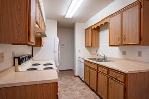 Fargo apartment for rent - A kitchen with wooden cabinets and a white refrigerator. Fargo, ND West Oak Apartments