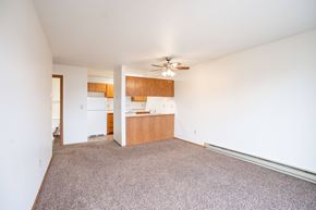 Fargo apartment for rent - A room with a ceiling fan and a kitchen area in the background. Fargo, ND Hawthorn Apartments