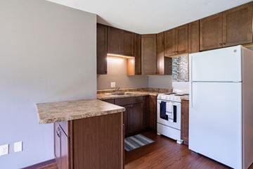 Little Canada apartment for rent - A kitchen with a white refrigerator and wooden cabinets.