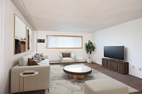 Fargo apartment for rent - A living room with a white couch, a brown armchair, a coffee table, and a television. Fargo, ND Park Terrace Apartments