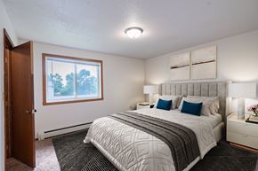 West Fargo apartment for rent - A bedroom with a large bed and a window overlooking trees. West Fargo, ND Clearview Apartments