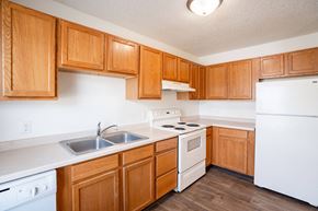West Fargo townhouse for rent - A kitchen with wooden cabinets and white appliances. West Fargo, ND Sheyenne Terrace Townhomes