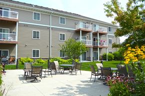 Fargo apartment for rent - The exterior of a three level apartment building with a grass and patio area out front. Fargo, ND Crossroads Apartments