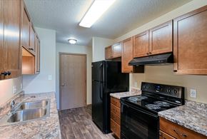 Grand Forks apartment for rent - Grand Forks, ND Madison Apartments. A kitchen with black appliances and a closet.