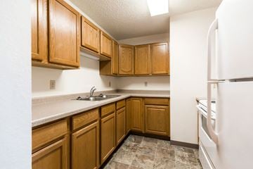 Bismarck apartment for rent - a kitchen with wooden cabinets and a sink and a refrigerator