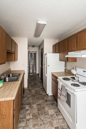 Crookston apartment for rent - Grand Forks, ND Barrette Arms Apartments. a kitchen with white appliances and wooden cabinets