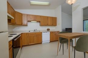 Fargo apartment for rent - a kitchen with white appliances and wooden cabinets with a small dining table. Fargo, ND Bridgeport Apartments