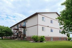 Fargo apartment for rent - the exterior of a building with a green lawn and trees. Fargo, ND Carlton Place Apartments