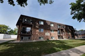 Fargo apartment for rent - a brick apartment building with a lawn and a blue sky