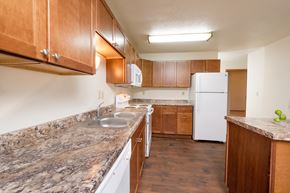 Fargo apartment for rent - a kitchen with marble counter tops and wooden cabinets and a white refrigerator. Fargo, ND Cedars 2 Apartments