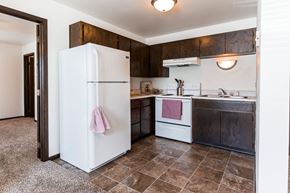 Grand Forks apartment for rent - Grand Forks, ND Claremont Apartments. A kitchen with white appliances and dark wood cabinets.