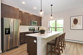 Eagan apartment for rent - a kitchen with wooden cabinets and a large island with a white countertop