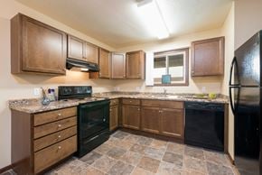 Bismarck apartment for rent - a kitchen with brown cabinets and black appliances at Highland Meadows in Bismarck, ND