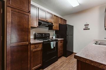 Grand Forks apartment for rent - a kitchen with black appliances and wooden cabinets