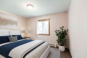 Bismarck apartment for rent - a bedroom with a bed and a plant and a window. Bismarck, ND Hannifin Apartments