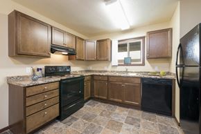 Bismarck apartment for rent - Bismarck, ND Highland Meadows Apartments. A kitchen with brown cabinets and black appliances