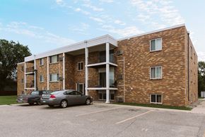Crookston apartment for rent - Grand Forks, ND Hoven Apartments. A brick apartment building with two cars parked in a parking lot