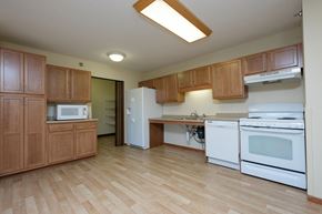 Fargo apartment for rent - a kitchen with white appliances and wooden cabinets. Fargo, ND Crossroads Apartments