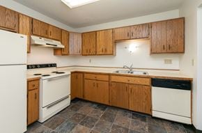 Fargo apartment for rent - a kitchen with white appliances and wooden cabinets. Fargo, ND Maplewood Bend Apartments