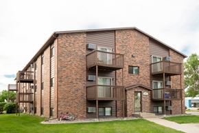 Fargo apartment for rent - a brick apartment building with balconies and a bike parked outside. Fargo, ND Maplewood Bend Apartments