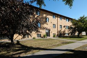 Fargo apartment for rent - a brick building with a sidewalk and trees in front of it. Fargo, ND Monticello Apartments