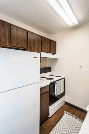 Crookston apartment for rent - Grand Forks, ND Riverwood Apartments. A kitchen with white appliances and wooden cabinets and a refrigerator