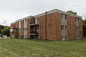 Crookston apartment for rent - Grand Forks, ND Riverwood Apartments. A red brick apartment building with a green yard