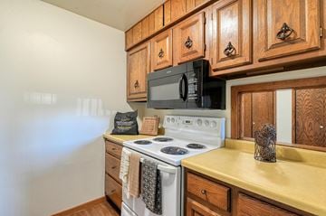 Grand Forks apartment for rent - a kitchen with a stove and microwave and wooden cabinets