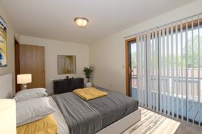 Fargo apartment for rent - a bedroom with a bed and glass sliding door to a patio. Fargo, ND South Pointe Apartments