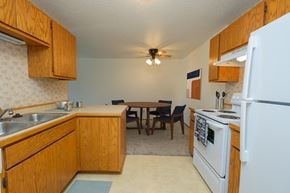 Fargo apartment for rent - Fargo, ND Sugarplum Apartments. A kitchen and dining room. The dining room has a table with four chairs around it with a ceiling fan and light directly above it.